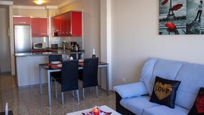 Un espacio habitable compacto con kitchenette, comedor y sofá con cojines decorativos.