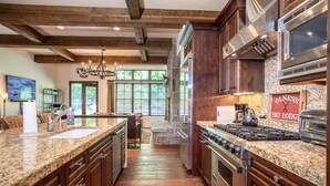 Una cocina amplia con encimeras de granito, armarios de madera, una estufa grande y una chimenea de piedra.