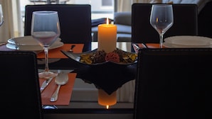 Une table à manger avec une bougie, des verres à vin et une assiette de fleurs séchées.