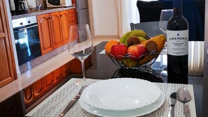 A kitchen with wooden cabinets, a microwave, a coffee maker, and a wine bottle on the table.