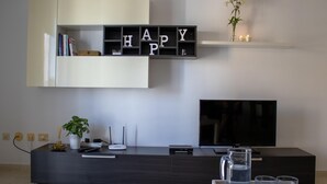 Un salon moderne avec un meuble de rangement en bois foncé, un meuble blanc placé au-dessus, et un support de télévision noir.
