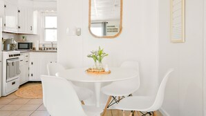 A modern kitchen with white cabinets, a microwave, stove, and a dining area with a white table and chairs. - Oceanfront condos with 3 night minimum rentals and linens included! (Ocean City)