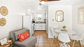 A modern kitchen with white cabinets, a dining area with white chairs, and a ceiling fan. - Oceanfront condos with 3 night minimum rentals and linens included! (Ocean City)