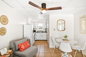 A modern kitchen with white cabinets, a dining area with white chairs, and a ceiling fan. - Oceanfront condos with 3 night minimum rentals and linens included! (Ocean City)