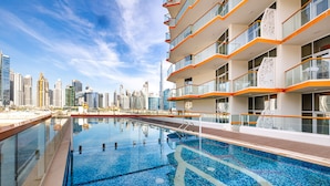 A swimming pool with a city skyline in the background. - Unlock Waters Edge (Dubai)