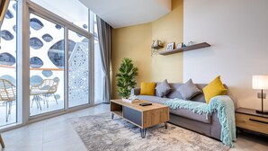 A modern living room with a sofa, coffee table, and a large window with a view of a building with unique architecture. - Unlock Waters Edge (Dubai)