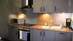 Une cuisine de taille réduite équipée d’un four à micro-ondes, d’une cuisinière, d’un évier et de placards.