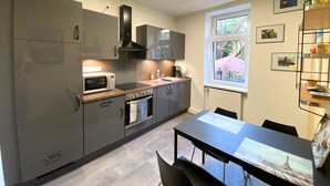 Une cuisine moderne avec des meubles gris, un four à micro-ondes, un four traditionnel et une fenêtre donnant sur un paysage verdoyant.