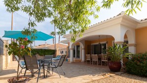 Un espace extérieur aménagé en terrasse, avec une table et des chaises, une plante en pot et un parasol bleu.