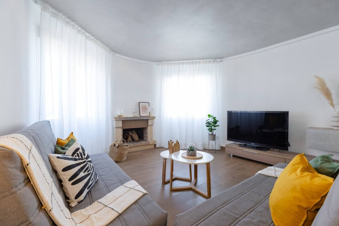 A living room with a sofa, a fireplace, a TV, and a dining table.