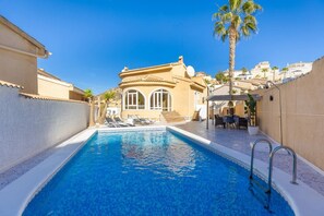 A swimming pool with lounge chairs, a covered patio, and a building with arched windows. - The Big Chill by Fidalsa (Ciudad Quesada)