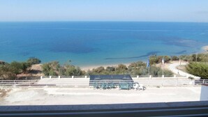 A coastal view with a beach, a fenced area with chairs, and a clear sky. - A terrace overlooking the sea 19084041C226886 (Sicilia)