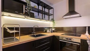 A modern kitchen with black cabinetry, a stainless steel sink, a built-in oven, and a microwave.