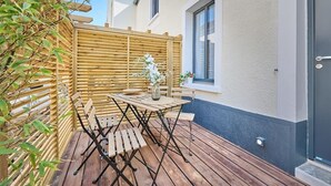 A wooden deck with a table and chairs, a wooden fence, and a window.