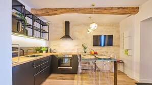 Una cocina moderna con una isla central, vigas de madera y un horno empotrado.
