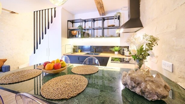 Una cocina moderna con encimera de mármol verde, un frutero y una roca decorativa.