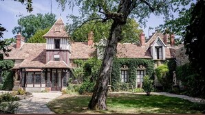 Una casa tradicional con una torre destacada y un jardín bien cuidado.
