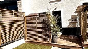 Un patio con cerca de madera, planta en maceta y pequeña zona de terraza.