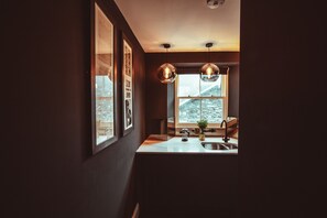 Eine moderne Küche mit großem Fenster, Pendelleuchten und einer Spüle.