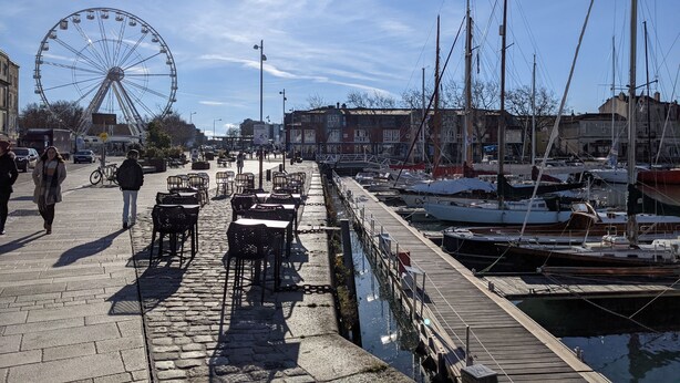 A marina with boats docked, a cobblestone walkway, and a Ferris wheel in the background. - Nice little house close to the sea and town center (La Rochelle)