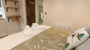 Un dormitorio con una cama, una puerta de madera y un perchero.