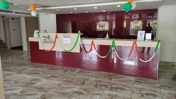 Zona de recepción de hotel con suelo de mármol, mostrador de recepción y vistas al exterior.