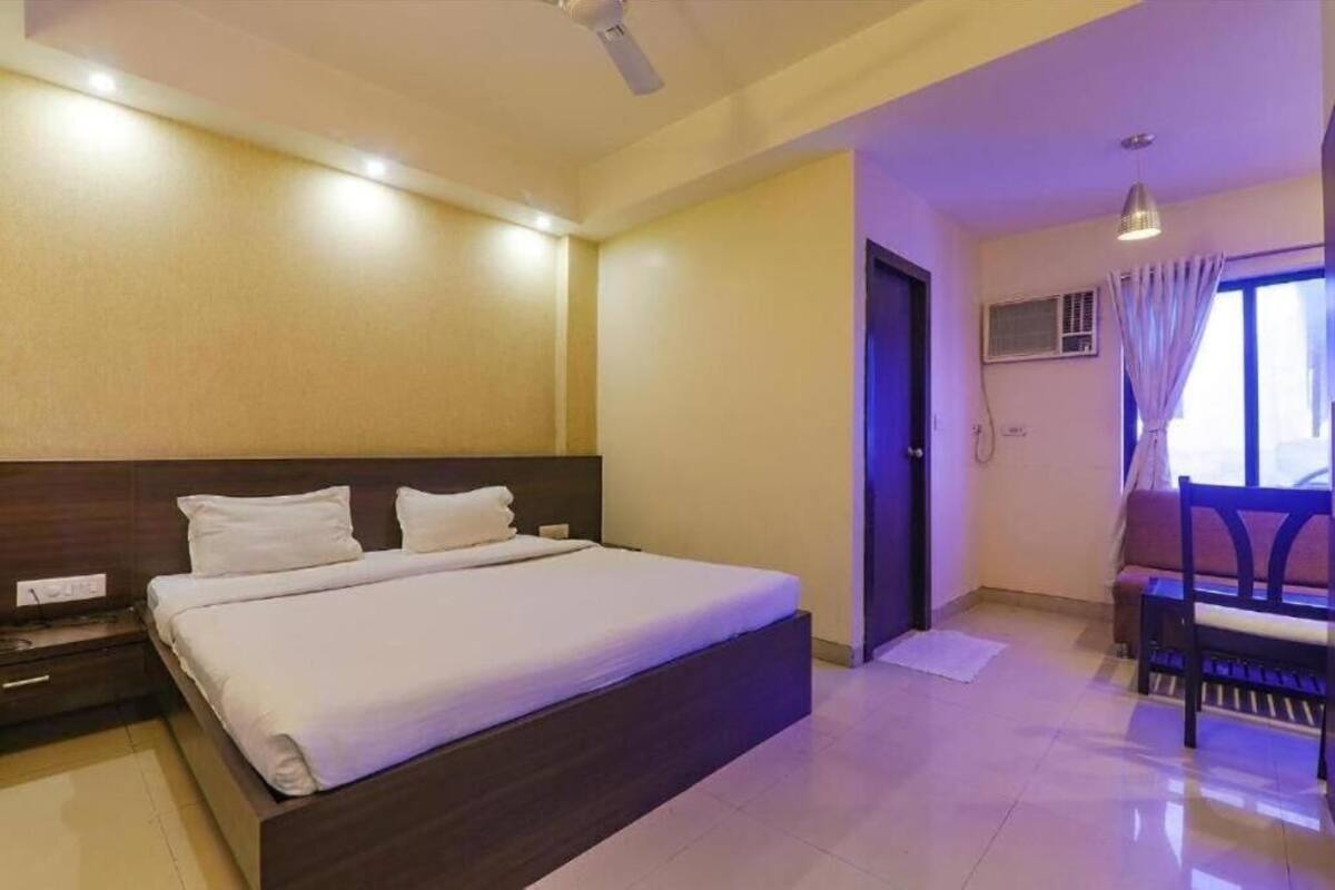 A hotel room with a bed, bedside table, and a window with curtains.