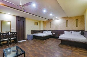 Habitación de hotel con dos camas, un escritorio, una silla, una mesita y un ventilador de techo.