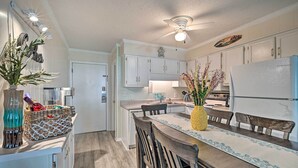 A kitchen with white cabinets, a dining table with chairs, a ceiling fan, and a refrigerator. - Myrtle Beach Condo w/ On-Site Pool & Beach Access (Myrtle Beach)