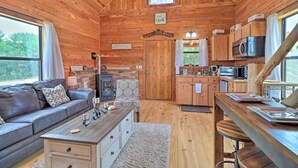 Un intérieur de chalet chaleureux, avec un revêtement en bois, une cheminée, un canapé, un coin repas et une cuisine.