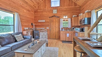 A cozy cabin interior with a wooden interior, a fireplace, a sofa, a dining area, and a kitchen.