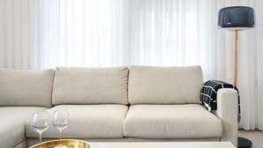 A modern living room with a beige sofa, a coffee table with a tray of glasses, and a floor lamp. - Yehuda Market Suite - One Bedroom Apartment, Sleeps 4 (Jerusalem)