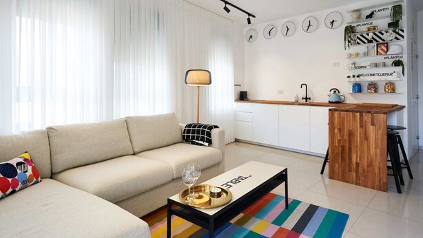 A modern living room with a sofa, a coffee table, and a kitchen area with a bar counter. - Yehuda Market Suite - One Bedroom Apartment, Sleeps 4 (Jerusalem)