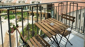 A balcony with a wooden table and chairs, overlooking a courtyard with buildings and construction sites. - Yehuda Market Suite - One Bedroom Apartment, Sleeps 4 (Jerusalem)