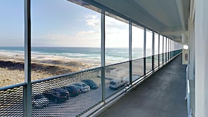 A corridor with large windows overlooking a beach and ocean. - Fontainebleau Terrace by Resort Collection (Panama City Beach)