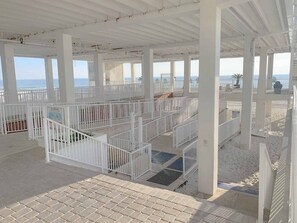 A beachside pavilion with white railings and a tiled floor, overlooking the ocean.