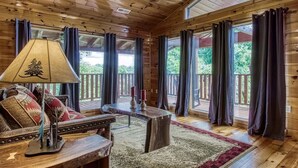 A wooden cabin interior with a sofa, a table, and a lamp.