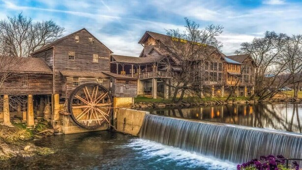 A historic water mill with large wooden structures and a waterfall.