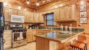 A wooden cabin kitchen with a central island, stainless steel appliances, and wooden cabinets.