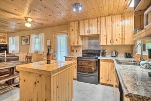 A wooden cabin interior with a kitchen featuring wooden cabinets, a granite countertop, and a built-in stove. - Hot Tub & Fire Pit: Pet-Friendly Clayton Escape! (Clayton)
