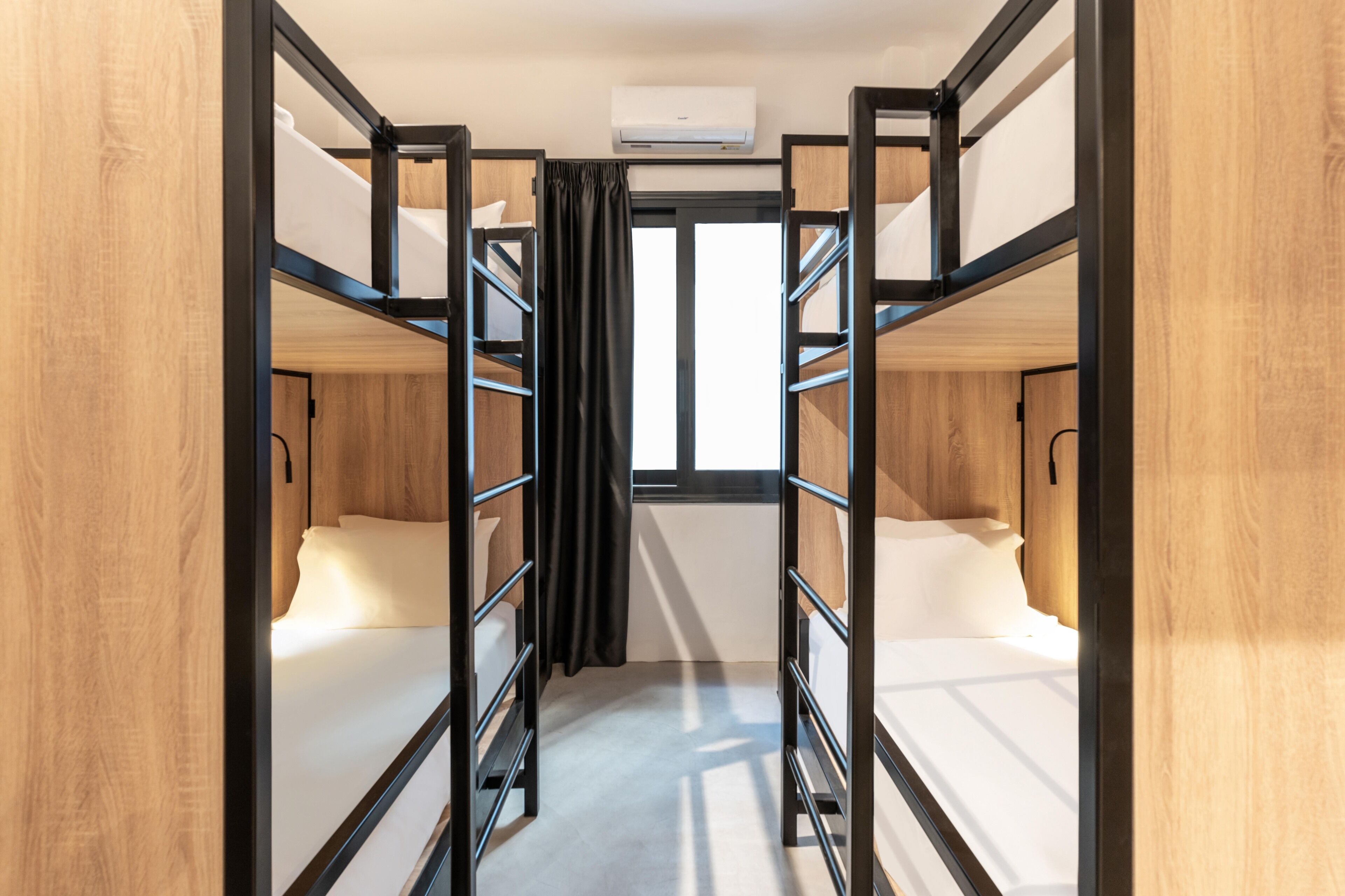Un dormitorio con literas, una ventana y un equipo de aire acondicionado.