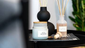 A black tray with a blue candle labeled "Wild Meadow," a white candle, and reed diffusers.