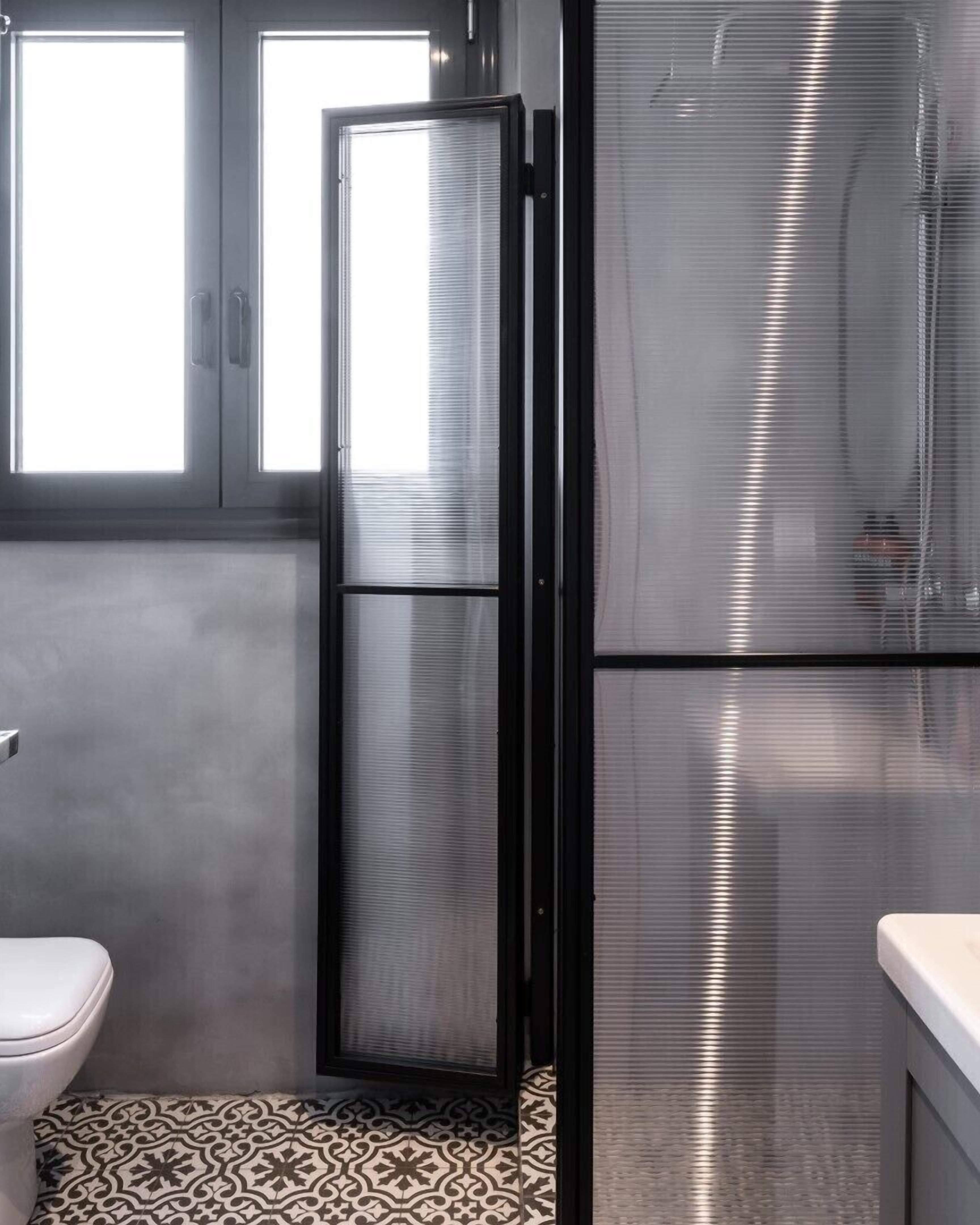 Un baño con inodoro, cabina de ducha y refrigerador de acero inoxidable.