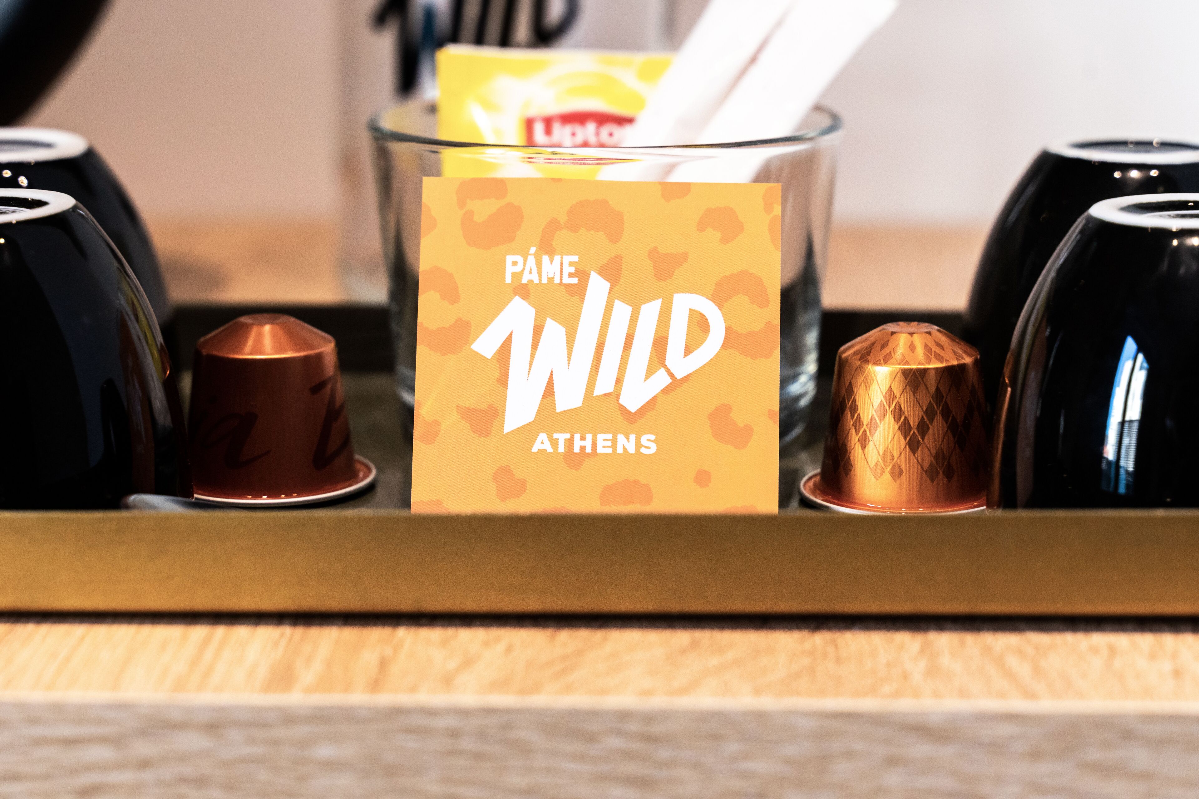 Una bandeja con un recipiente de vidrio etiquetado "PÂME WILD ATHENS" y tres tazas con un diseño geométrico.