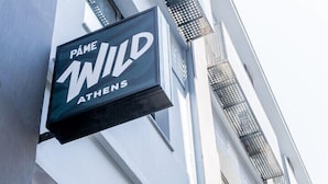 Un bâtiment sur lequel on peut lire l’inscription : « PAME WILD ATHÈNES ».