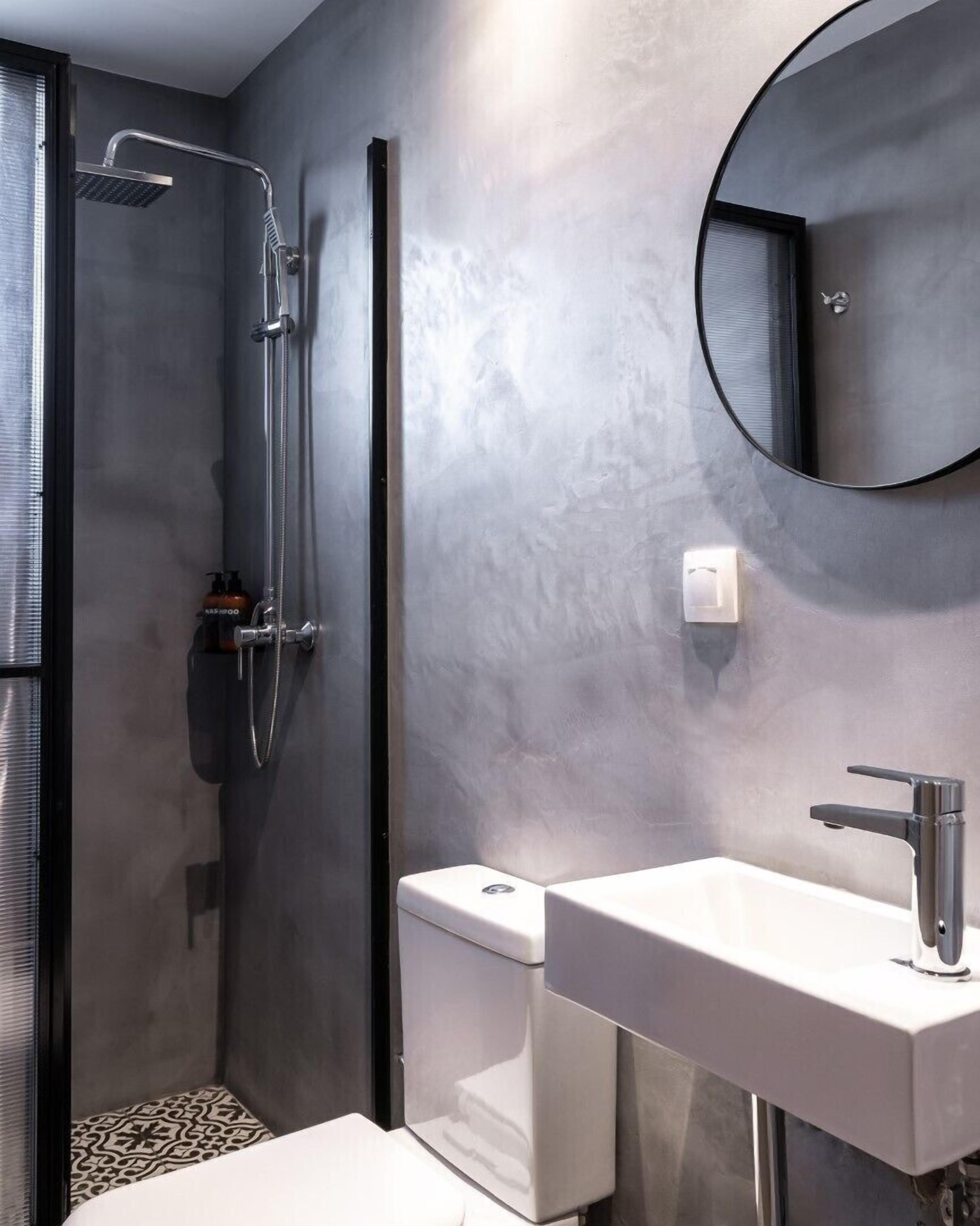 Un baño moderno con ducha a ras de suelo, lavamanos independiente y un espejo grande.