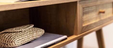 A wooden desk with a book open on it, a laptop, and a woven basket.