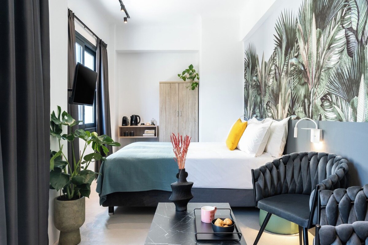Une chambre à coucher moderne avec un lit, une chaise noire, une table basse et une grande plante.