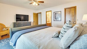 Ein Schlafzimmer mit Bett, Fernseher, Kommode und Deckenventilator.