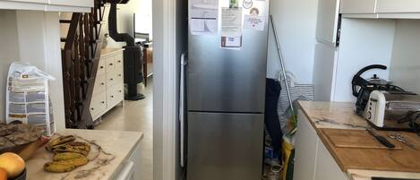Compact kitchen with a refrigerator, microwave, washing machine, and sink, plus a staircase to the upper level.